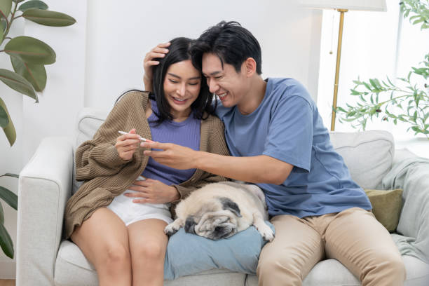 Couple celebrates a joyful moment while checking a positive pregnancy test at home with their pug dog