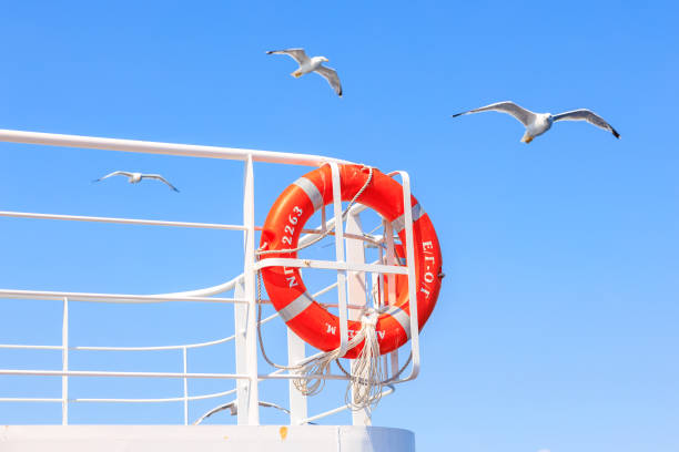 A red life preserver is on a railing next to a blue sky. August 5, 2024 Ferry from Keramoti to Thassos island Greece