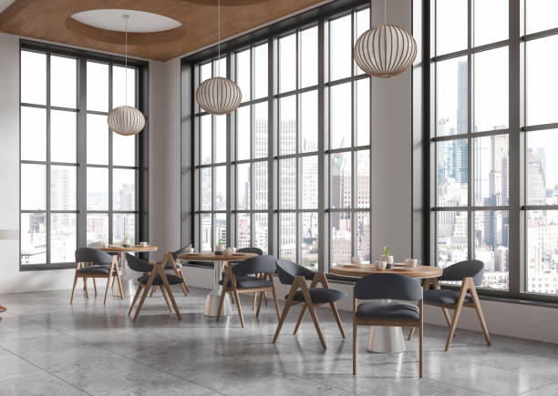 istock Modern cafe interior with large windows and city view, featuring wooden tables and chairs, minimalist ceiling lights, and cozy seating. 3D Rendering 2192479709