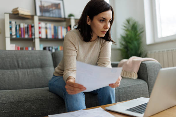 istock Woman reviewing financial documents while working on her laptop at home 2192481542