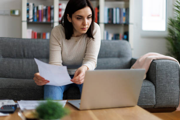 istock Woman reviewing financial documents while working on her laptop at home 2192481776