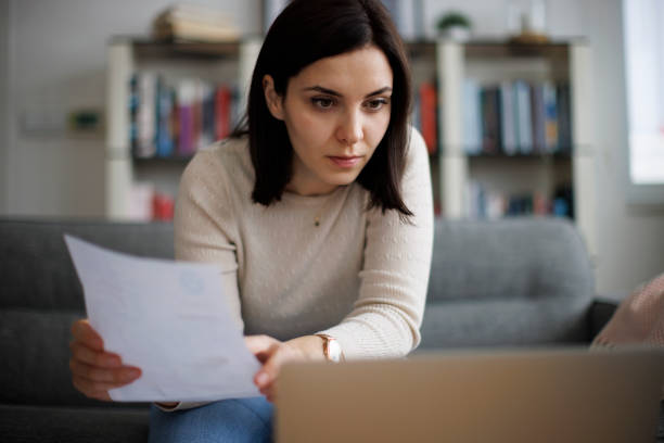 istock Woman reviewing financial documents while working on her laptop at home 2192481793