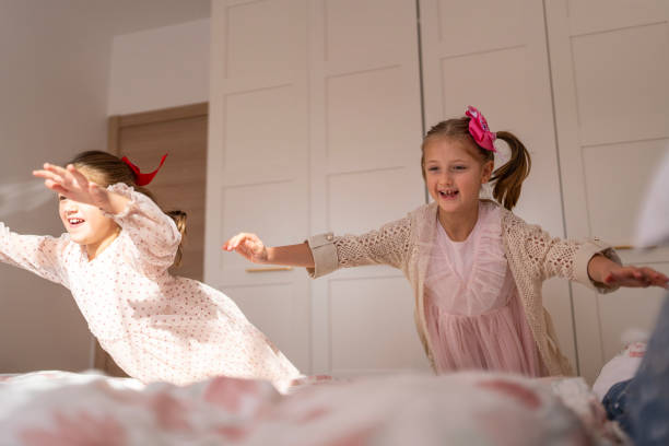 istock Two kids jumping joyfully on a bed in a bright bedroom 2192484667