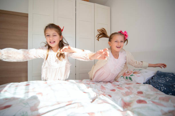 istock Two children joyfully jumping on a bed in a bright cozy room 2192484859