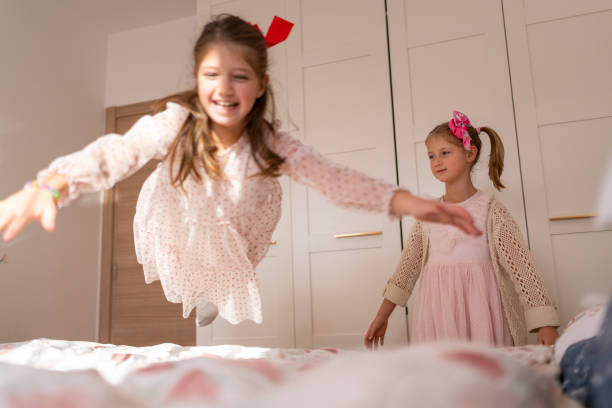 istock Two happy children jumping and playing on a bed together indoors 2192484888
