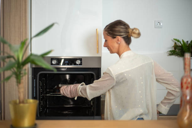 istock Woman removing tray from oven in modern kitchen setup 2192485015