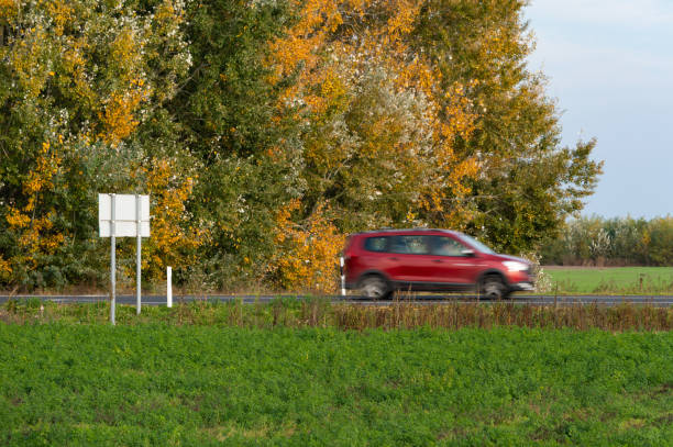 istock Red car driving by autumn trees 2192488560
