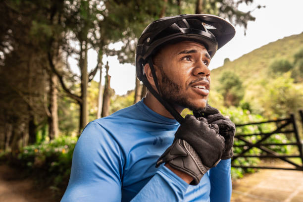 Young cyclist putting on helmet outdoors