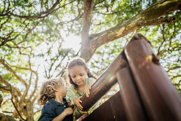 Two Smiling Children Leaning On Fence On Walk In Countryside