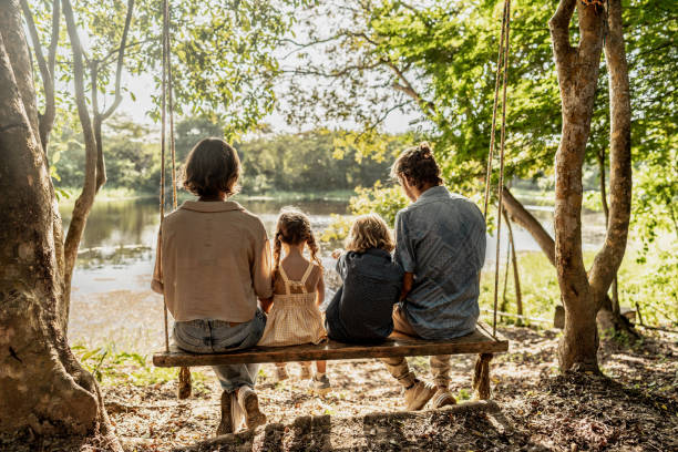 istock Family sitting on a swing by the lakeside 2192489148
