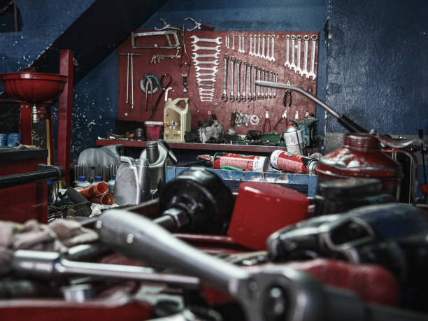 Scattered repair tools in an auto repair shop, with wrenches neatly lined up on the wall across.