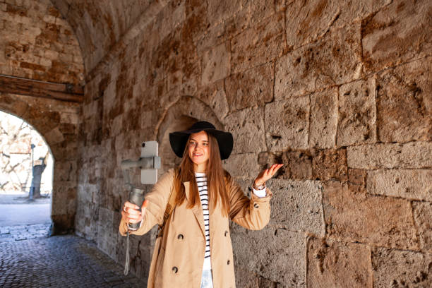 With hat and bright smile, this young content creator striding through picturesque locations, filming her travel stories to inspire her followers