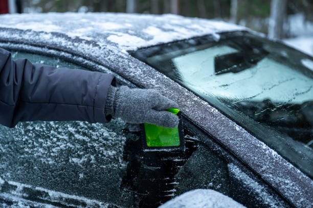 istock Removing frost from car window with green scraper in winter scene 2192492512