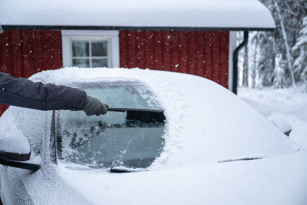 istock man remove her car from snow with brush. Car wash concept. 2192492681
