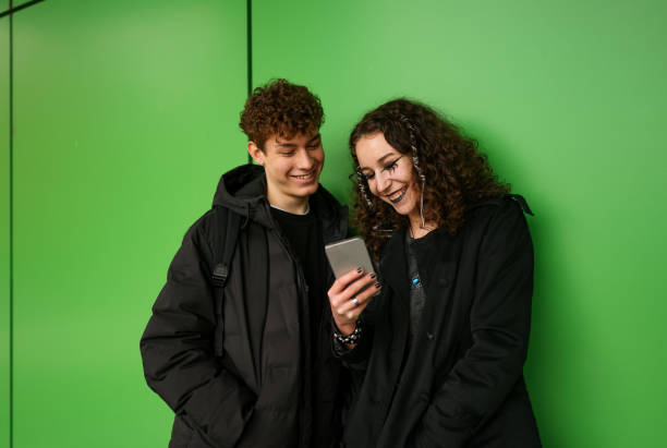 istock Grunge duo using smart phone in front of green wall outdoor 2192494191