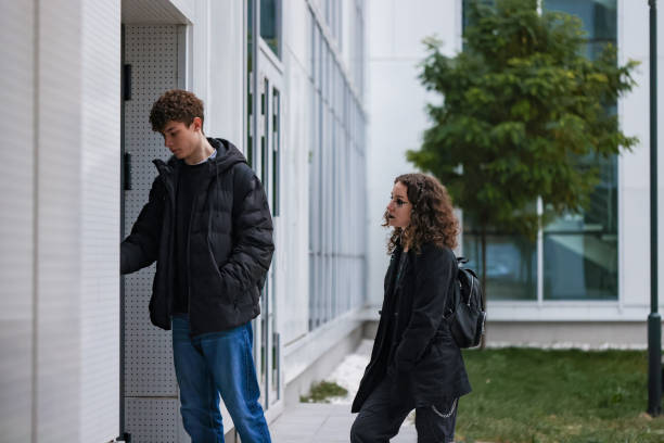 istock Teenagers in dark clothing walking by a sleek modern structure 2192496327