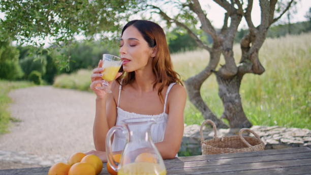 istock Smiling model drinking juice enjoying under tree closeup. Woman holding drink 2192496434