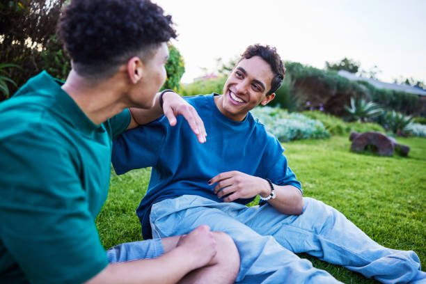 istock Best friends sitting on grass and talking and smiling 2192496849