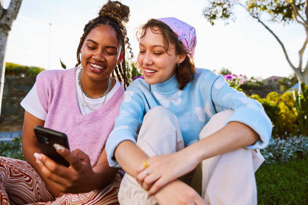 istock Two female friends using mobile phone and smiling 2192496883
