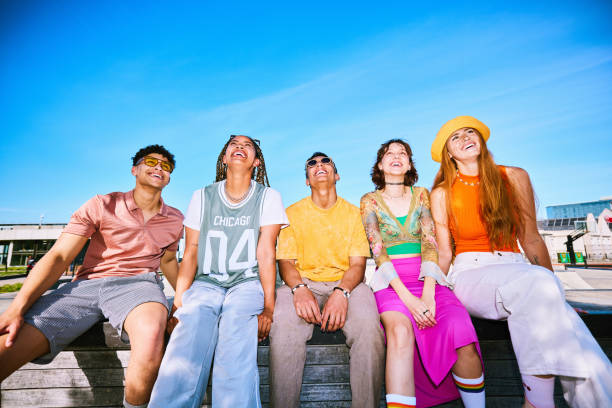 Group of five friends having fun and socialising in skatepark stock photo