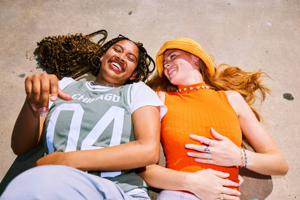 istock High angle view of two young women lying on backs, laughing, side by side 2192496949