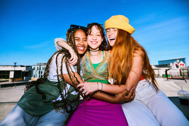 istock Three female friends smiling and embracing with arms around each other 2192496977