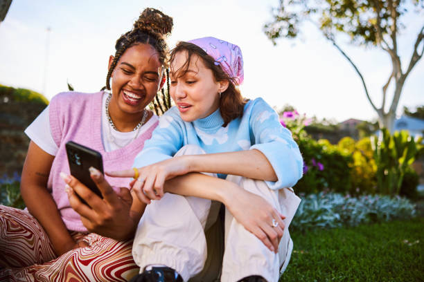 Young woman holding smartphone, her friend pointing at screen stock photo