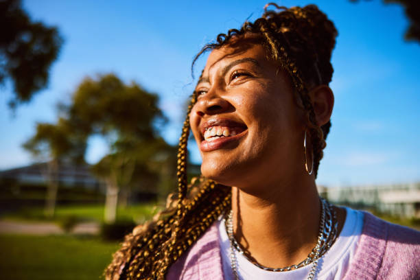 Headshot of young woman with braided hair looking away, toothy smile stock photo