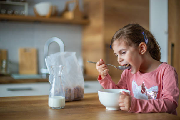 istock Happy little girl having breakfast at home in the kitchen 2192497216