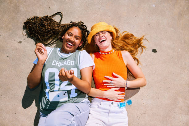 Cheerful female friends hanging out in skatepark, one with mobile on tummy