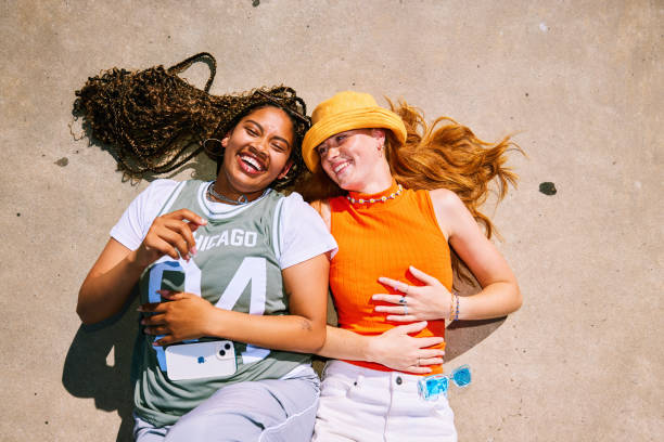 istock High angle view of two young women lying down on their backs on concrete, smiling 2192497284