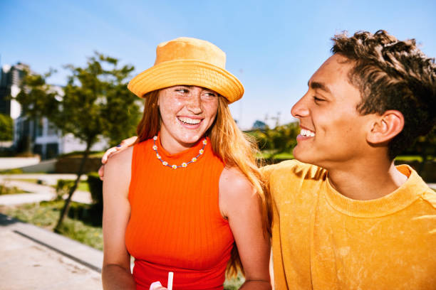 Candid portrait of cheerful young woman wearing yellow hat smiling at boyfriend stock photo
