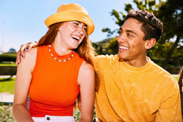 Candid portrait of cheerful young couple, woman wearing yellow hat, laughing stock photo
