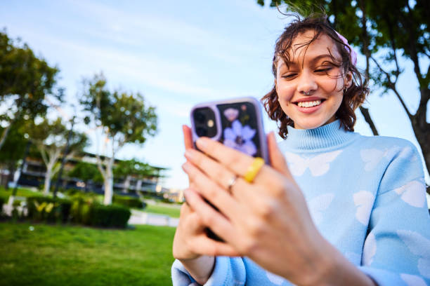 istock Cheerful young woman holding smartphone and texting 2192497414