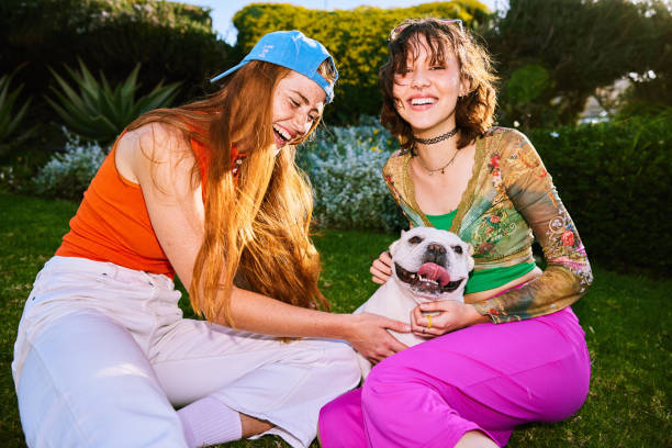 istock Two cheerful female friends playing with pet dog 2192497449