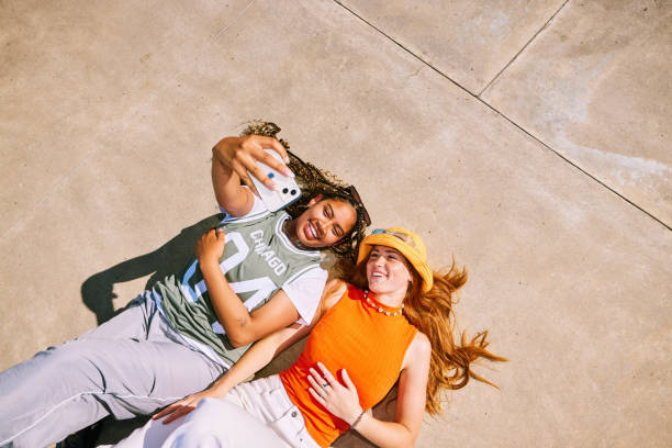 istock Two best friends lying on backs, side by side, taking selfie on phone 2192497617