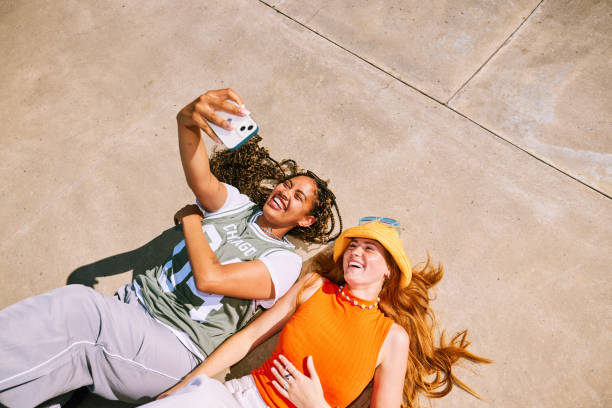 istock Two best friends laughing and lying side by side, taking selfie on smartphone 2192497894