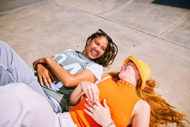 Two female friends lying on backs, side by side, smiling and talking