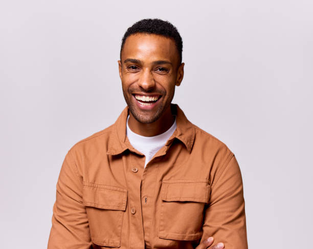 Studio portrait of happy multiracial mid adult man wearing brown shirt, toothy smile stock photo
