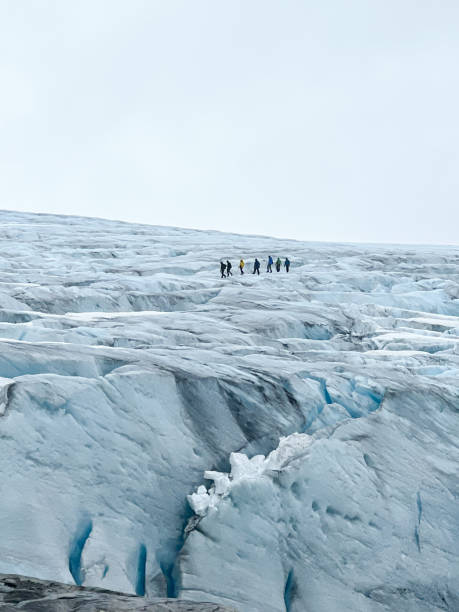 istock Group of unrecognizable hikers chained together on a rope walking across the Austdalsbreen glacier with a ground full of crevasses in Jostedal, Norway, in a white environment 2192500173