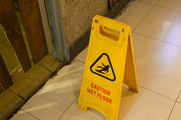 Set against a daytime hallway backdrop, the yellow warning board cautions passersby of slippery conditions.