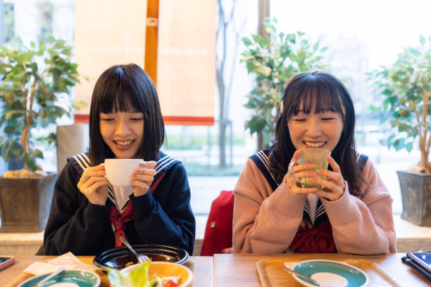 istock Female friends in school uniform having tea break in cafe 2192501955