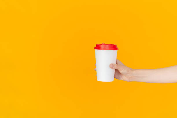 istock A woman's hand holding a white paper coffee cup with a red lid. Copy space. Mock up. 2192504162