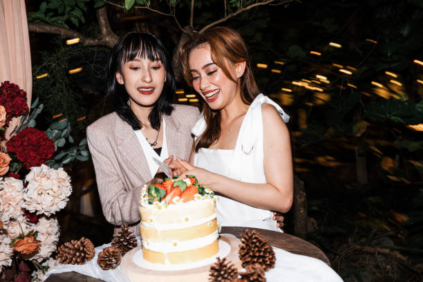 istock Romantic wedding moment featuring brides sharing a cake adorned with fresh berries and pinecones, celebrating love and unity in a charming outdoor ceremony. 2192511452