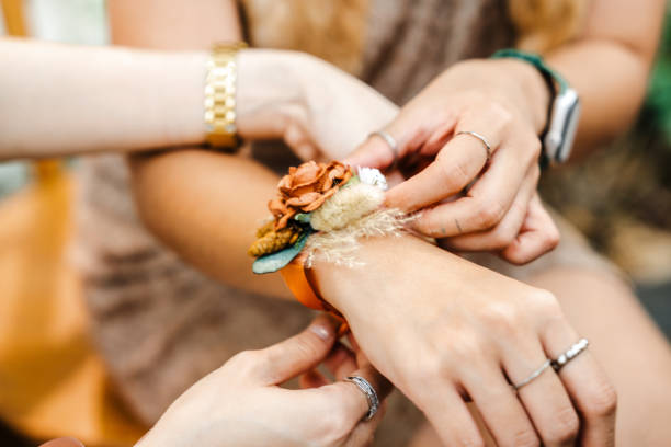A close-up view of hands adjusting a beautiful floral wrist corsage, showcasing elegance, craftsmanship, and sentimental bonding at a wedding celebration.