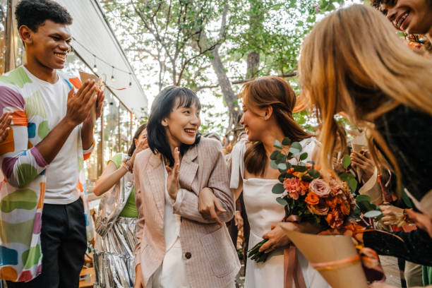 LGBTQ wedding scene with two brides enjoying their special day, surrounded by guests applauding and celebrating their love in a colorful garden atmosphere.