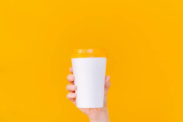 istock A woman's hand holding a white paper coffee cup with an orange lid. Empty space. Mock up. 2192512599