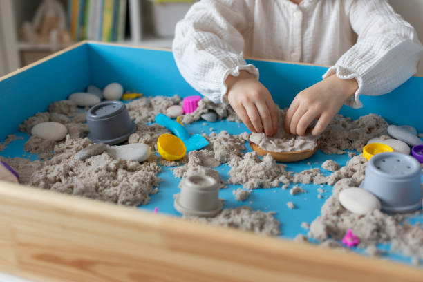 istock Children activity with kinetic sand for motor and sensory development. Toddler play therapy with toys in sandbox. 2192513326