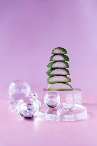 Layers of fresh aloe slices arranged creatively on a clear display against a calming purple background