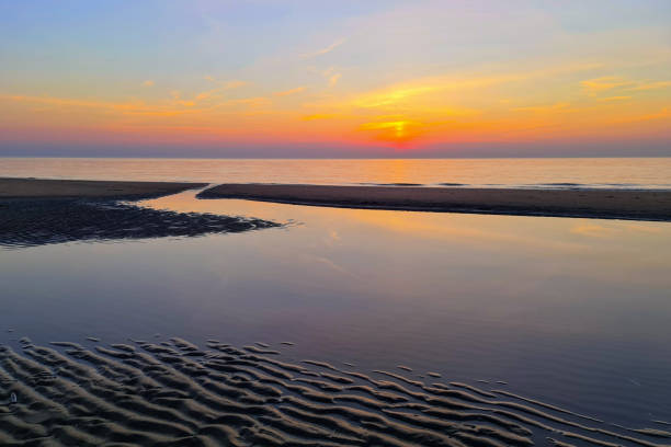 Sunset and its reflection at a beach in the Netherlands.